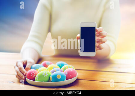 close up of hands with easter eggs and smartphone Stock Photo