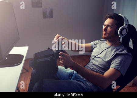 man playing car racing video game at home Stock Photo