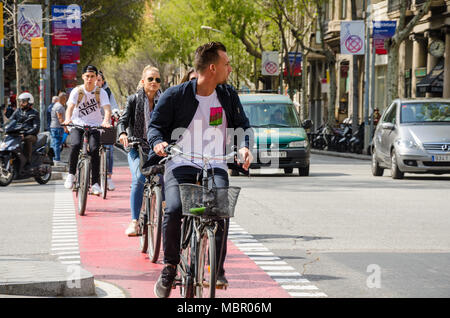 Cyclists cycle down a bicycle land alongside a busy street in Barcelona, Spain. Stock Photo