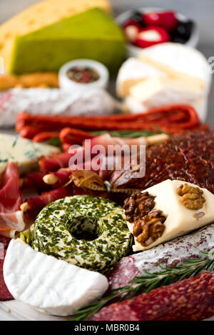 Traditional italian antipasto, cutting board with salami, cold smoked meat, prosciutto, ham, cheeses, olives, capers on grey background. Cheese and meat appetizer. Stock Photo