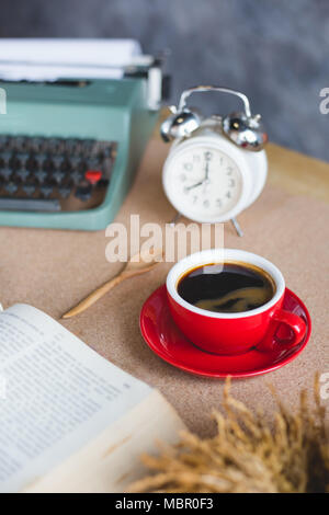 A cup of coffee with typewriter and alarm clock  and book on table Stock Photo