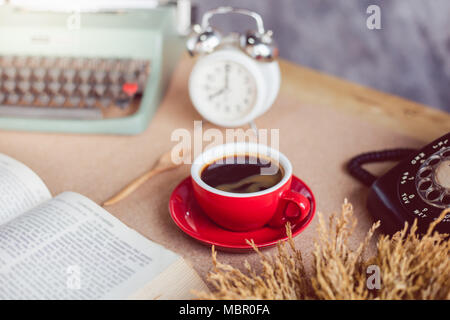A cup of coffee with typewriter and alarm clock  and book on table Stock Photo