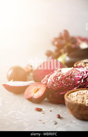 Clean eating concept. Raw purple vegetables on gray concrete background. Violet eggplant, beets, cauliflower, purple beans, plums, onion, grape, quinoa, rice. Ingredients for cooking, copy space Stock Photo