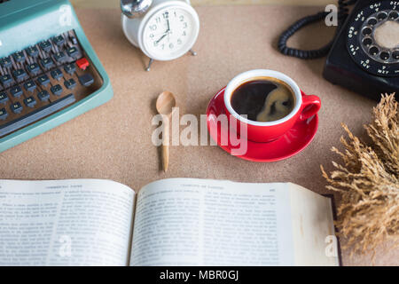 A cup of coffee with typewriter and alarm clock  and book on table Stock Photo