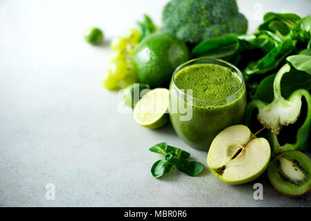 Glass with green health smoothie, kale leaves, lime, apple, kiwi, grapes, banana, avocado, lettuce. Copy space. Raw, vegan, vegetarian, alkaline food concept. Stock Photo