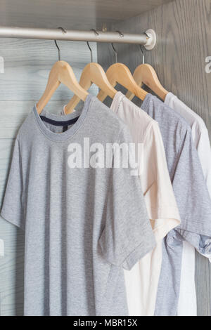T-shirt hanging on wood hanger on rack in cloth wardrobe Stock Photo
