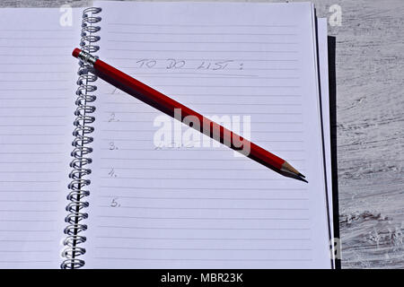 Red pencil with notebook on wooden table Save creative ideas on paper. Basic equipment before the computer. On the rustic table background Stock Photo