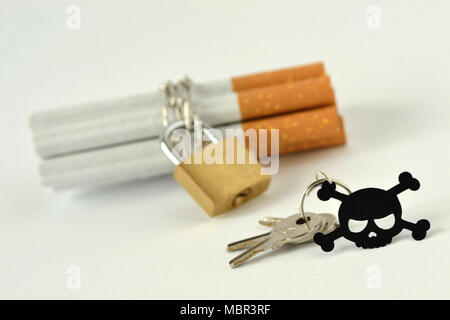 Cigarettes with chain and padlock and key with black skull on white background - Stop smoking concept Stock Photo