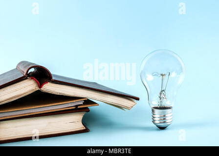 Books and light bulb on blue background close-up Stock Photo