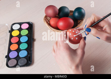 Closeup photo of woman holding egg and painting it with brush. Easter concept Stock Photo