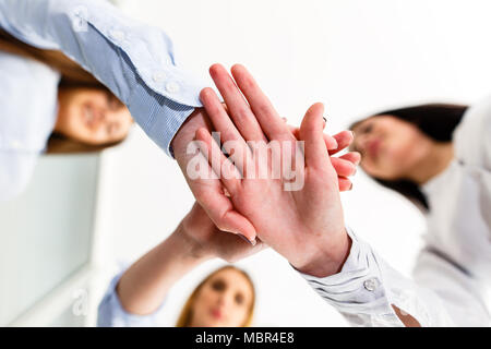 Three successful women celebrate their success by getting their hands together Stock Photo