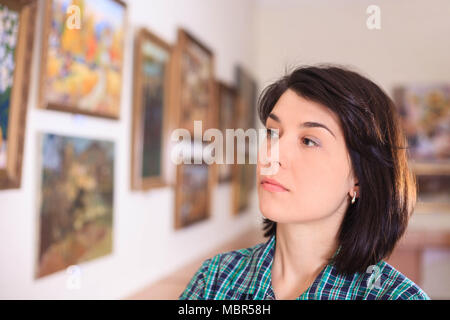 Young woman looking at painting in art gallery. Stock Photo