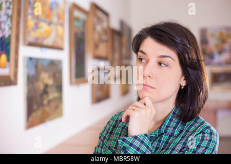 Young woman looking at painting in art gallery. Stock Photo