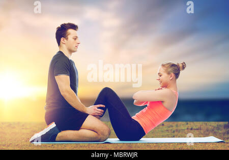 happy sportive couple doing sit-ups outdoor Stock Photo