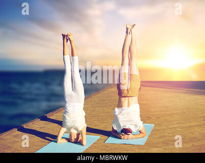 couple doing yoga headstand on mat outdoors Stock Photo