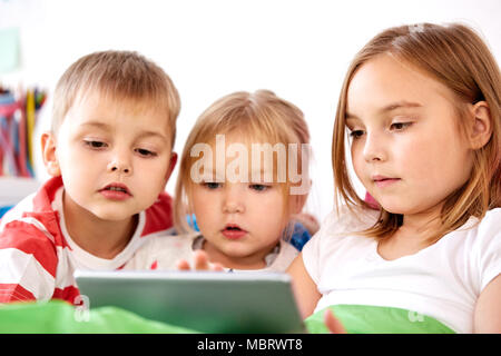 little kids with tablet pc in bed at home Stock Photo