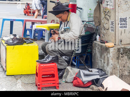 A male Vietnamese cobbler working on the sidewalk, repairing a shoe, Ho Chi Minh City, Vietnam. Stock Photo