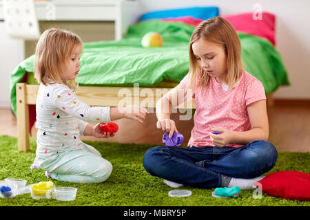 sisters with modelling clay or slimes at home Stock Photo