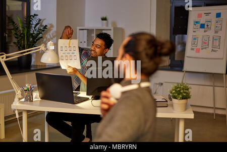 creative man showing papers to colleague at office Stock Photo