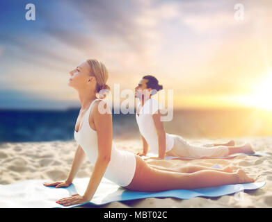 couple doing yoga and cobra pose on beach Stock Photo