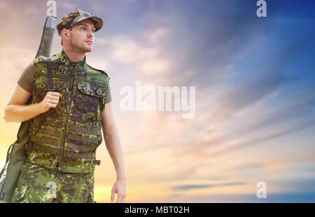 young soldier or hunter with gun over sky Stock Photo