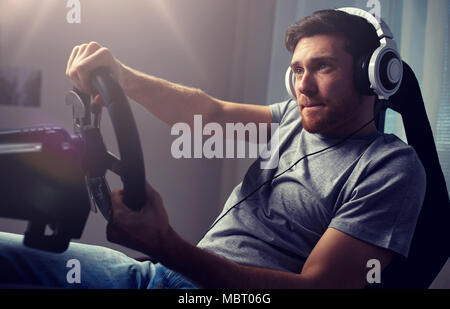 man playing car racing video game at home Stock Photo