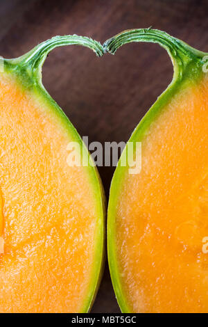 The space between two halves of a melon and its stalk forms a heart shape. Stock Photo