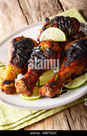 jamaican jerk chicken drumstick with lime closeup on a plate on a table. vertical Stock Photo