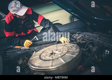 Vintage Car Mechanic Trying to Fix Classic Car. Huge Big Block Engine Restoration. Stock Photo