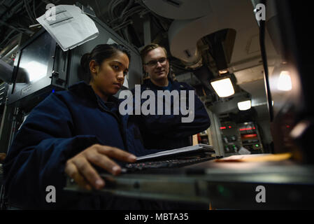 USS Theodore Roosevelt (CVN 71) is a Nimitz-class nuclear-powered aircraft carrier operating with Carrier Strike Group 9 in U.S. 5th Fleet. The archival image records information systems technicians monitoring communication systems aboard the carrier in the Arabian Gulf on January 4, 2018. Stock Photo