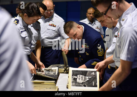 Coast Guard Cutter Mellon crewmembers look through photo albums prior to a ceremony held in the Base Seattle gymnasium on Jan. 9, 2018, which celebrated the cutter’s 50 years of service. The Mellon was designed to help crewmembers perform each of the Coast Guard’s missions including search and rescue, defense operations, law enforcement and environmental protection. U.S. Coast Guard photo by Petty Officer 2nd Class Ali Flockerzi. Stock Photo