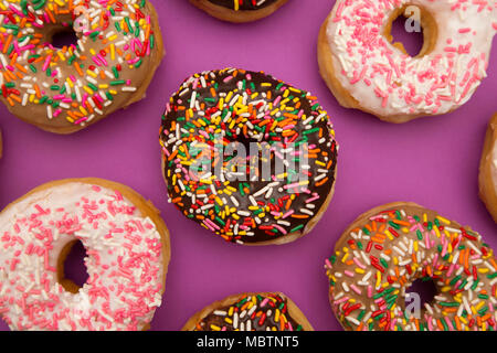 A Background of Various Sprinkle Donuts on a Purple Background Stock Photo