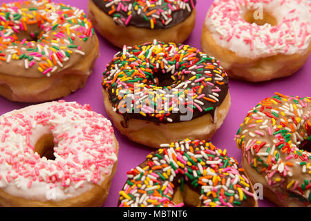 A Background of Various Sprinkle Donuts on a Purple Background Stock Photo
