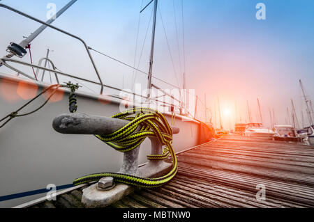 yacht moored in a marina, close up of metal cleat and ropes mooring the boat Stock Photo