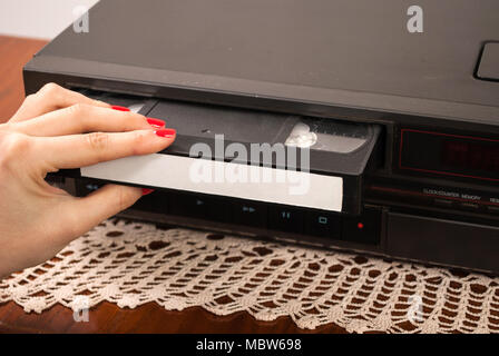 Woman hand inserting blank VHS cassette in old video recorder Stock Photo