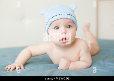 Little funny baby boy with big blue eyes smiling with cute cap with ears on his head. Indoor Stock Photo