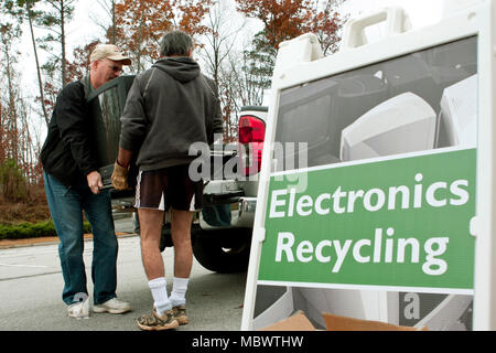 Two men carry a discarded television set past an "Electronics Recycling" sign at a recycling event on November 23, 2013 in Lawrenceville, GA. Stock Photo