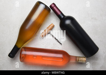 Cabernet, Rose, Chardonnay: Overhead view of a group of three different bottles arranged in a triangle with a corkcscrew in the middle. Stock Photo