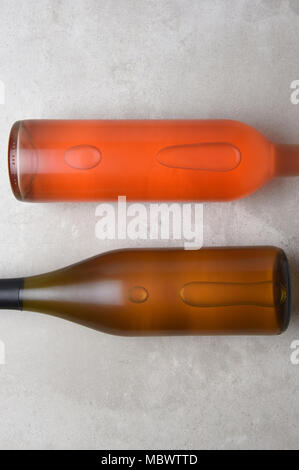 Chardonnay and Blush Wine Bottles: Two bottles on a concrete table top with copy space at the top and bottom of the frame. Stock Photo