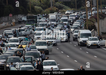 Tel Aviv, Israel. 12th April, 2018. People exit their cars on a highway and observe two minutes of silence to mark the Yom HaShoah (Holocaust and Heroism Remembrance Day), which commemorates approximately six million Jews who perished in the Holocaust that was carried out by Nazis, in Tel Aviv, Israel, 12 April 2018. Yom HaShoah is an annual occasion on which an air raid siren sounds throughout the whole country. While almost everything comes to a complete halt, Israelis are expected to observe two minutes of solemn reflection while the siren is sounded. Credit: dpa picture alliance/Alamy Live Stock Photo