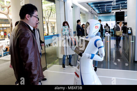 Shanghai, China. 12th Apr, 2018. A customer talks with a robot at the entrance of a self-service area of Jiujiang Road branch of China Construction Bank (CCB) in Shanghai, east China, April 12, 2018. Customers are able to transact 90 percent of cash and non-cash business in the self-service area of the branch. Credit: Fang Zhe/Xinhua/Alamy Live News Stock Photo