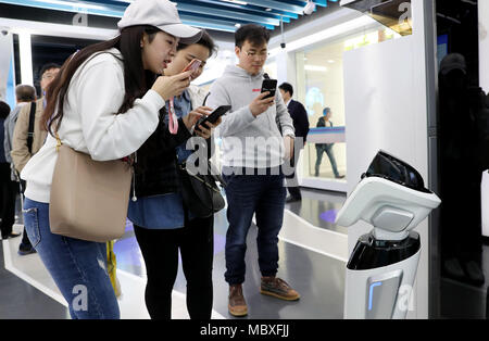 Shanghai, China. 12th Apr, 2018. Citizens consult a robot in a self-service area of Jiujiang Road branch of China Construction Bank (CCB) in Shanghai, east China, April 12, 2018. Customers are able to transact 90 percent of cash and non-cash business in the self-service area of the branch. Credit: Fang Zhe/Xinhua/Alamy Live News Stock Photo