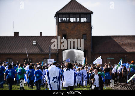 Oswiecim, Poland. 12th Apr, 2018. Participants wave Israeli flags at the main gate of the former Nazi German Auschwitz-Birkenau death camp during the 'March of the Living' at Oswiecim. The annual march honours Holocaust victims at the former Nazi German Auschwitz-Birkenau death camp in southern Poland. Credit: Omar Marques/SOPA Images/ZUMA Wire/Alamy Live News Stock Photo