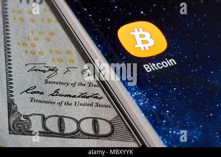 New york, USA - April 11, 2018: Bitcoin icon app on smartphone close-up on dollar currency background Stock Photo