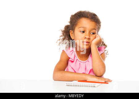 Education. Close up portrait of african little girl is sitting at the table with a notebook for drawing, isolated on white background Stock Photo