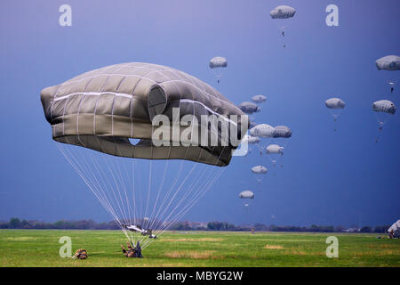 A U.S. Army Paratrooper assigned to the 173rd Airborne Brigade, Italian Army Paratroopers assigned to Folgore Brigade and Poland Paratroopers prepares to land after exiting a U.S. Air Force C-130 Hercules aircraft at Juliet Drope Zone in Pordenone, April 10, 2018. The 173rd Airborne Brigade is the U.S. Army Contingency Response Force in Europe, capable of projecting ready forces anywhere in the U.S. European, Africa or Central Commands' areas of responsibility. (U.S. Army photo by Paolo Bovo) Stock Photo