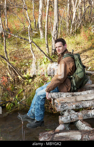 Tourist sits on a bridge over creek Stock Photo