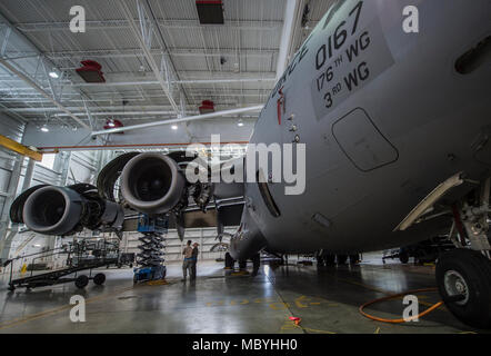 A C-17 Globemaster III assigned to the 176th Wing sits inside a hangar for a home station check at Joint Base Elmendorf-Richardson, Alaska, March 27, 2018. The 3rd and 176th maintenance squadrons complete an in-depth, four-day scheduled inspection of a C-17 approximately every 180 days. A home station check is the behind-the-scenes maintenance that can prevent loss of life, lead to savings in time and money and keep the aircraft fit to fight. Stock Photo