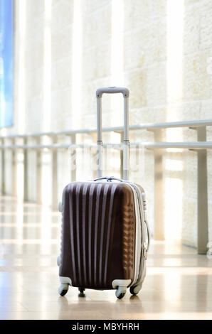 Packed travel suitcase, airport. Summer holiday and vacation concept. Traveler baggage, brown luggage in empty hall interior. Copy space Stock Photo