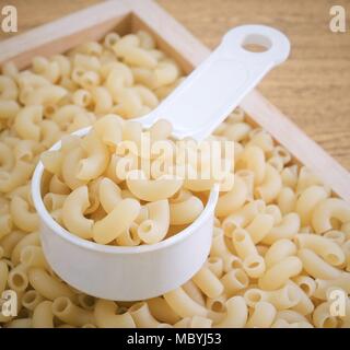Food and Cuisine, Uncooked and Dried Elbow Macaroni or Gomiti Pasta in Plastic Measuring Cup. Stock Photo